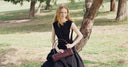 Woman holding a brown handbag in a park setting
